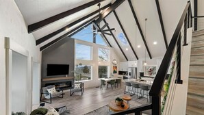 A spacious living area with a fireplace, dining table, and kitchen area.
