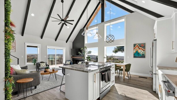 A modern kitchen with a central island, large windows, and a view of the outdoors.