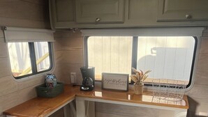 Une cuisine compacte dotée d’un plan de travail en bois, d’une machine à café et d’une fenêtre offrant une belle vue.