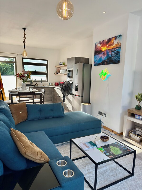 Un salon moderne avec un canapé bleu, une table basse et un coin repas offrant une vue agréable.
