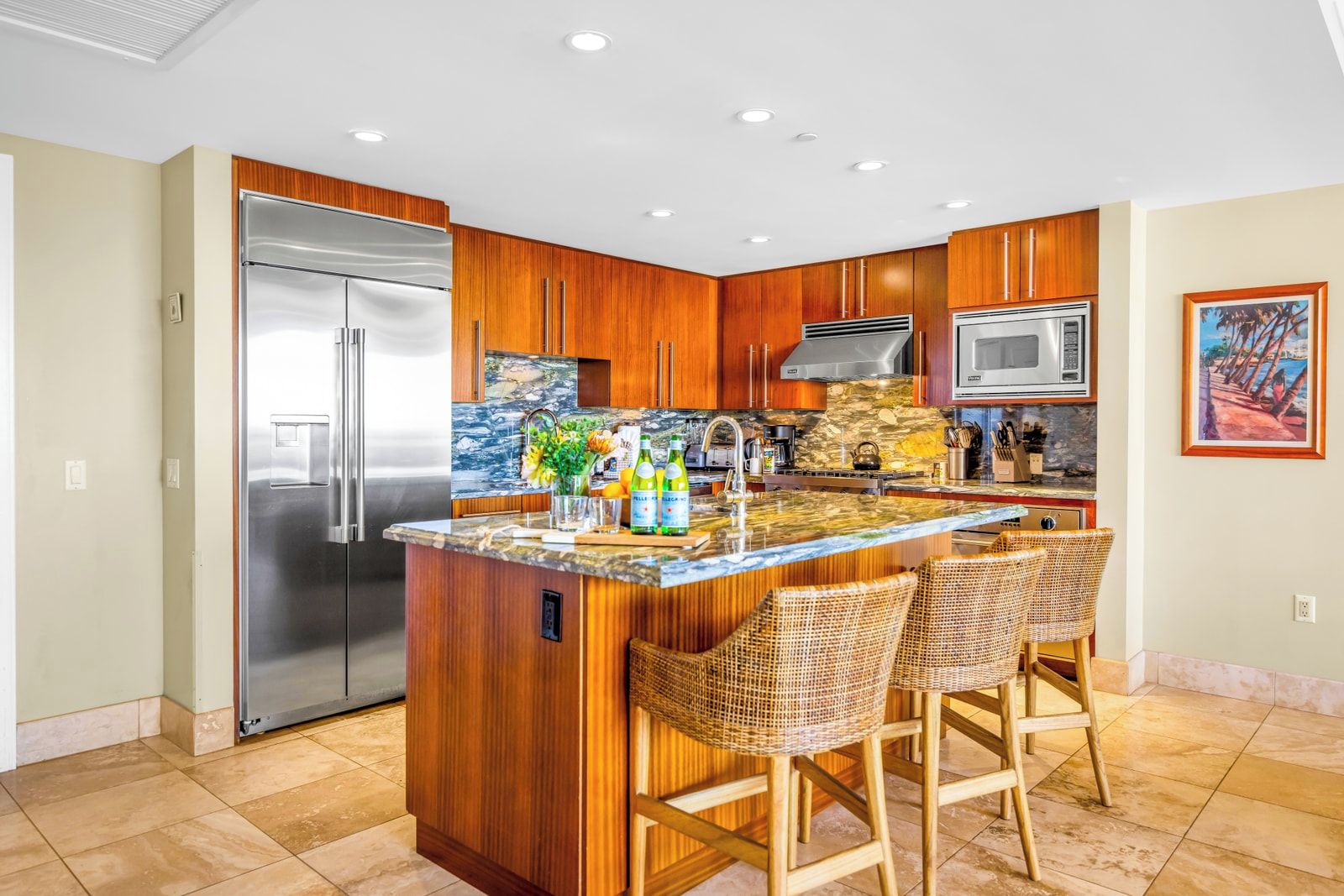 A modern kitchen with wooden cabinets, stainless steel appliances, a central island with bar stools, and a stone backsplash.