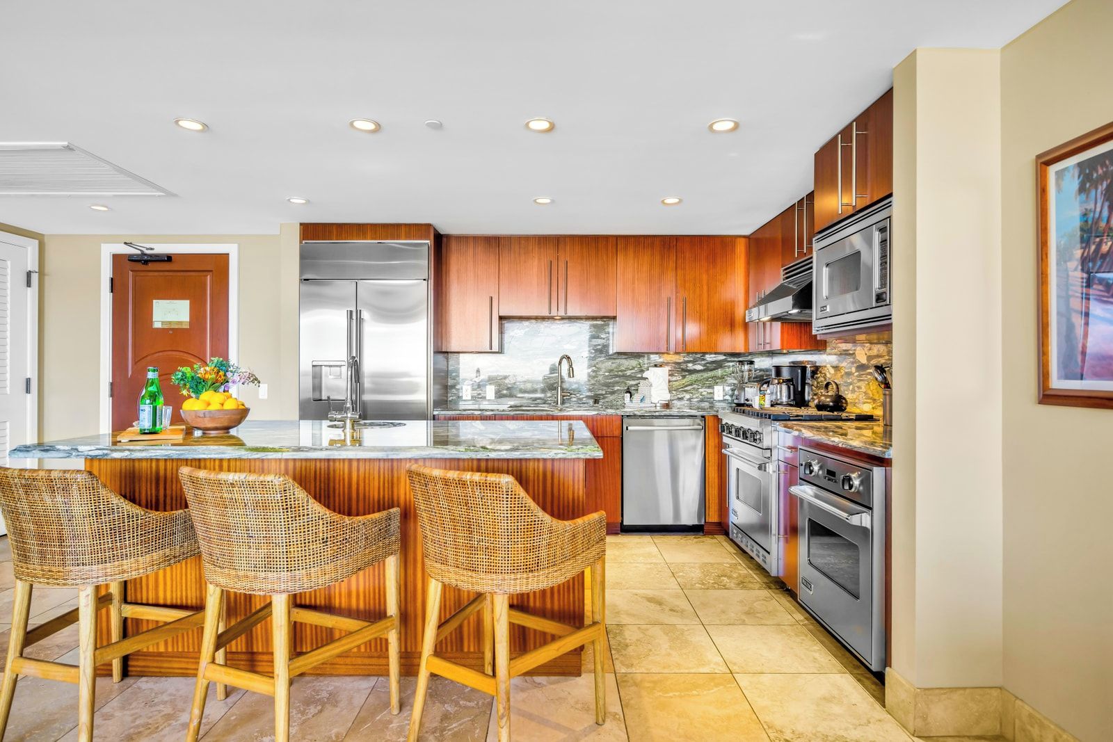 A modern kitchen with wooden cabinets, stainless steel appliances, a marble island, and wicker bar stools.