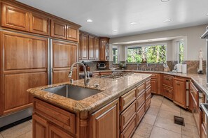 A kitchen with wooden cabinets, granite countertops, and a large island. - Grand Oriole Estate - Luxury Estate | Pool, Hot Tub, Game Room (Big Bear Lake)