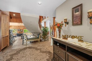 A spacious lobby with a grand staircase, a reception desk, and a decorative wall with a welcome sign. - Grand Oriole Estate - Luxury Estate | Pool, Hot Tub, Game Room (Big Bear Lake)