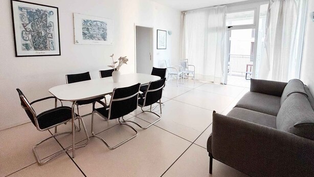 Un salon moderne comprenant une table à manger, des chaises, un canapé et des œuvres d’art accrochées aux murs.