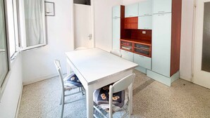Une pièce avec une table blanche, deux chaises, une armoire et une porte.
