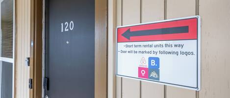 A door labeled '120' with a sign indicating short-term rental units and marked by Airbnb, B, and other logos.