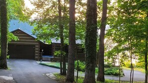 A building with a metal roof, surrounded by trees and a paved driveway. - Lakefront, Private Dock, Water Toys, Sunset Views! (Jefferson City)