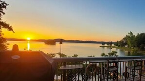 A deck with chairs and a table overlooking a lake at sunset. - Lakefront, Private Dock, Water Toys, Sunset Views! (Jefferson City)