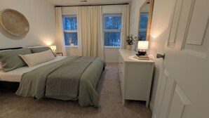 A bedroom with a bed, bedside tables, a dresser, a mirror, and windows with curtains. - Adorable home between Duke and UNC alongside trails (Durham)