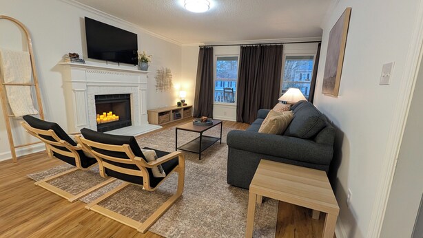 A living room with a fireplace, a sofa, a coffee table, and a TV. - Adorable home between Duke and UNC alongside trails (Durham)