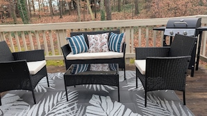 A deck with wicker furniture, a grill, and a view of a wooded area. - Adorable home between Duke and UNC alongside trails (Durham)