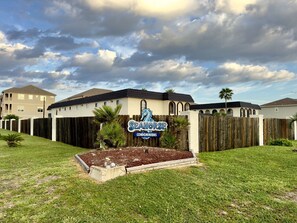 A residential area with a sign for 'SeaHorse Condominiums' and a wooden fence. - Starfish Stay | Tranquil Pool | Directly Across From Beach (Corpus Christi)
