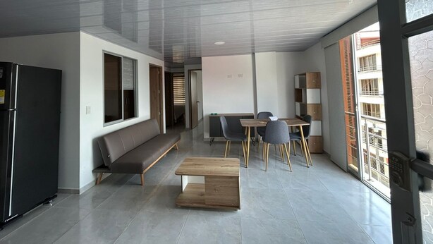 Una sala de estar moderna con sofá, mesa de centro y comedor.