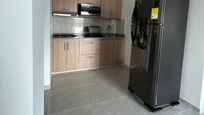 Una cocina con gabinetes de madera, un refrigerador de acero inoxidable y un microondas.