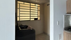 Una cocina moderna con estufa integrada, una ventana con persianas y un refrigerador pequeño.