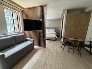 A modern hotel room with a sofa, a dining table with chairs, a bed, and a TV. - CASA SUE LIVING & HOTEL  (Bogotá)