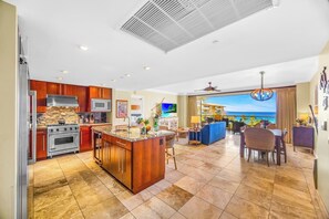 Une cuisine moderne dotée d’un grand îlot central, un coin repas avec vue et un salon donnant sur la piscine.