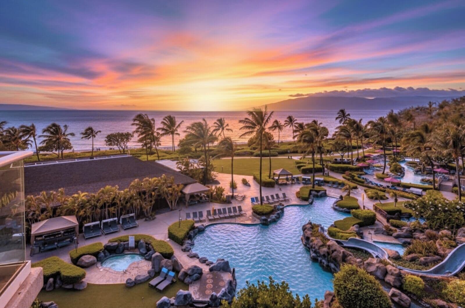 A resort with a pool area, lounge chairs, and palm trees.