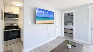 Cozinha moderna com micro-ondas, forno e televisão de tela plana na parede.