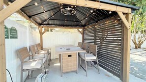 Une terrasse couverte avec une table et des chaises, un luminaire au plafond et un panneau indiquant que cet espace doit être maintenu propre.