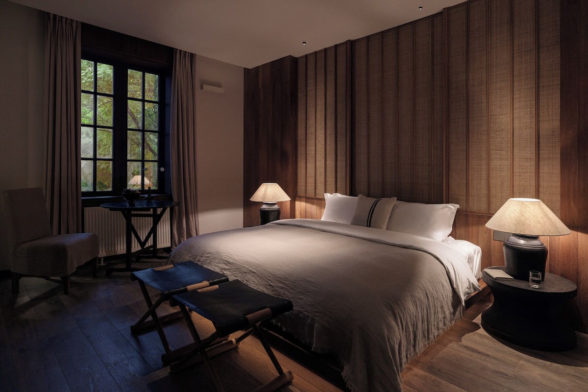 A bedroom with a large bed, two bedside tables with lamps, a