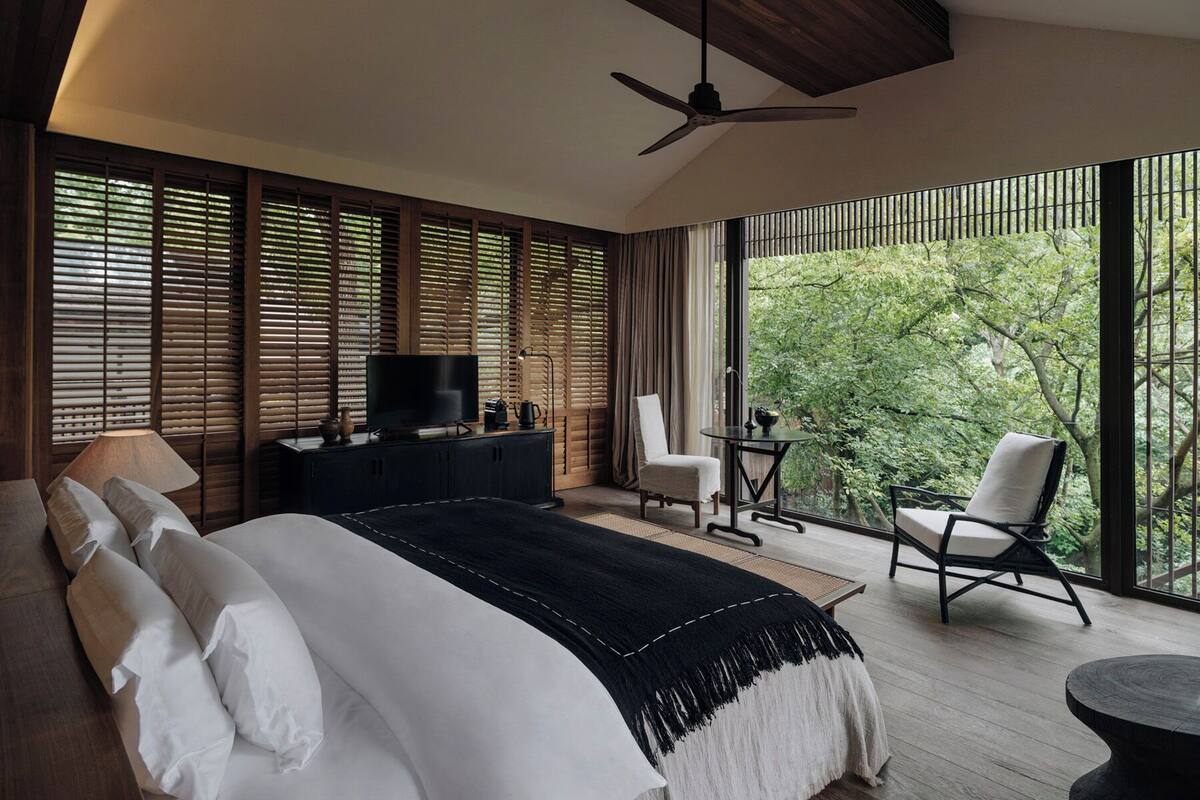 A bedroom with a bed, a TV, a desk, and a chair.