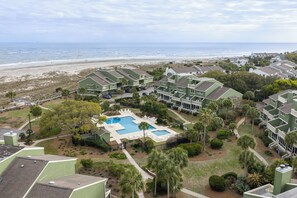 A resort with multiple green buildings, a central pool, and a beach view. - 2-story Condo with Private Balcony, Ocean Views and Community Pool (Isle Of Palms)