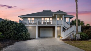 Een twee verdiepingen tellend huis met een overdekte garage, een balkon en een trap naar de bovenverdieping.
