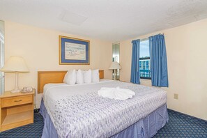 Hotelkamer met een bed, twee nachtkastjes, een lamp, een ingelijst beeld aan de muur en een raam met gordijnen.