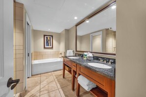 Une salle de bain avec une baignoire, deux lavabos, un grand miroir et un tableau encadré au mur.