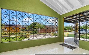 Ein Zimmer mit großem Fenster, grünen Wänden und einer Decke mit sichtbaren Balken.