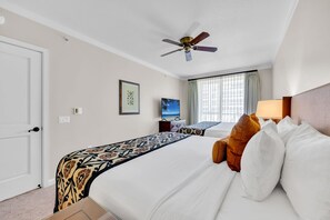 Ein Hotelzimmer mit Bett, Deckenventilator, Fernseher und einem fenster mit Vorhängen.