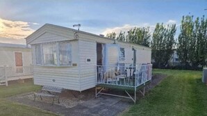 Een kleine, gelijkvloerse stacaravan met een omheinde patio en een klein terras.
