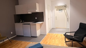 Een compacte leefruimte met een kitchenette, een eethoek en een aparte zithoek.