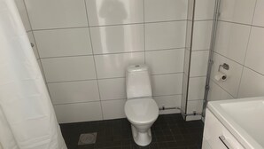 Een badkamer met een toilet, douche en bad.