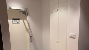 Een kamer met een grijze betegelde vloer, een houten vloerafdeling, een witte kast en een witte muur met een lichtschakelaar.
