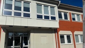 Een gebouw met twee verdiepingen, een glazen ingang, een plat dak en een bakstenen gevel.
