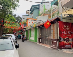A street with buildings, a Vietnamese flag, and a Min Hotel sale banner. - Min Hotel Ha Noi (Yen Hoa)
