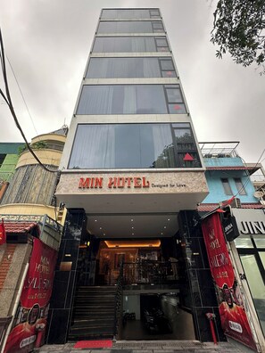 Un edificio de varios pisos con un cartel que dice 'MIN HOTEL' en la entrada.