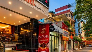 Un hotel con un llamativo anuncio de rebajas, una escalera visible y una fachada con letrero de salón de belleza.