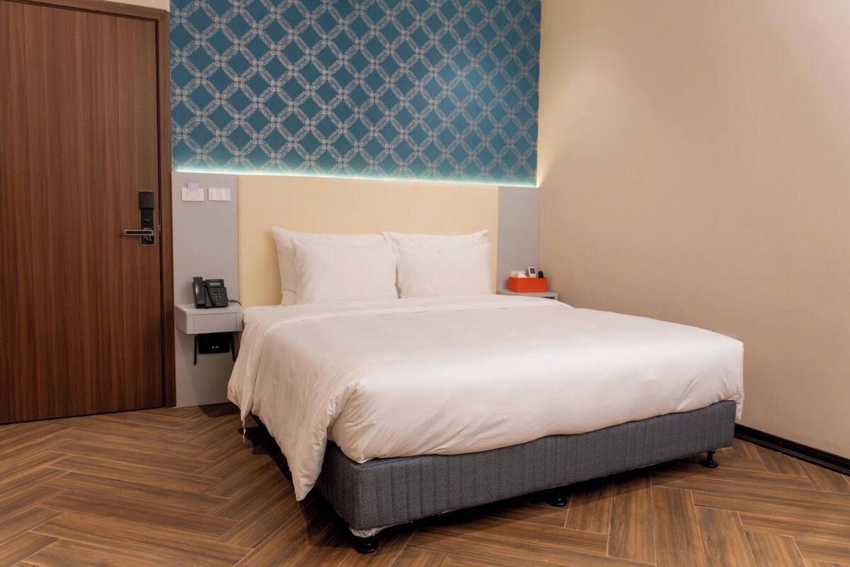 A hotel room with a bed, bedside table, and a patterned wall.
