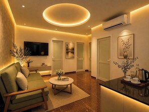 A modern living room with a sofa, a coffee table, a flat-screen TV, and a kitchen area with a countertop and appliances. - Soléa Boutique Hotel (Ben Thanh)