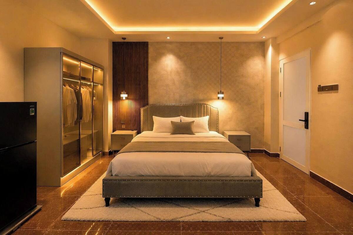 A modern hotel room with a large bed, a wardrobe, a minibar, and a bathroom.