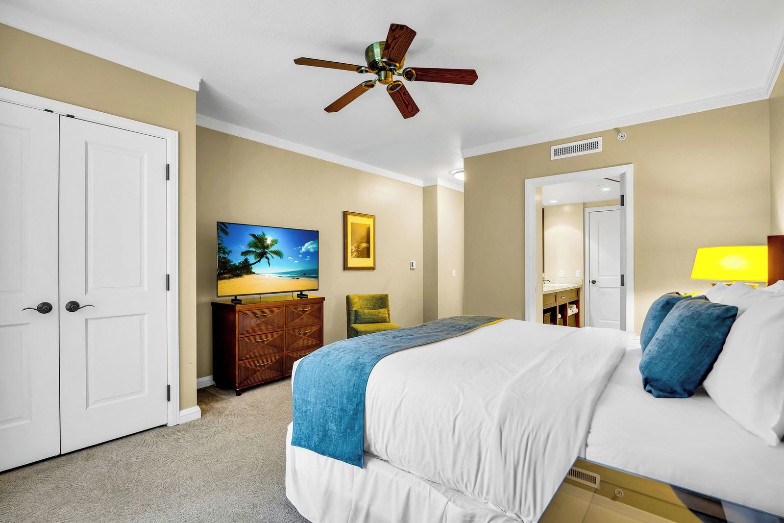 Een hotelkamer met een bed, plafondventilator, televisie, bureau en een badkamer.