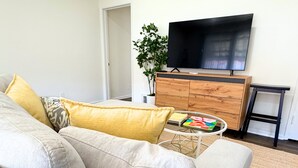 A living room with a sofa, a coffee table, a TV, a wooden cabinet, and a potted plant. - Newly Renovated, Quiet 2BR w/ Private Garage - Central LA (Los Angeles)
