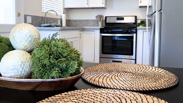 A kitchen with white cabinets, a stainless steel oven, and a wooden table with woven placemats. - Newly Renovated, Quiet 2BR w/ Private Garage - Central LA (Los Angeles)