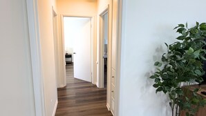 A hallway with wooden flooring, white walls, and a potted plant. - Newly Renovated, Quiet 2BR w/ Private Garage - Central LA (Los Angeles)
