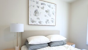A bedroom with a bed, a bedside table, a lamp, and a wall-mounted artwork. - Newly Renovated, Quiet 2BR w/ Private Garage - Central LA (Los Angeles)