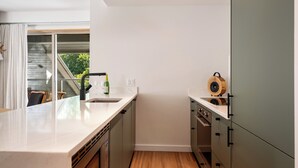Una cocina moderna con una isla grande, electrodomésticos integrados y un ventanal corredero que da a un balcón.